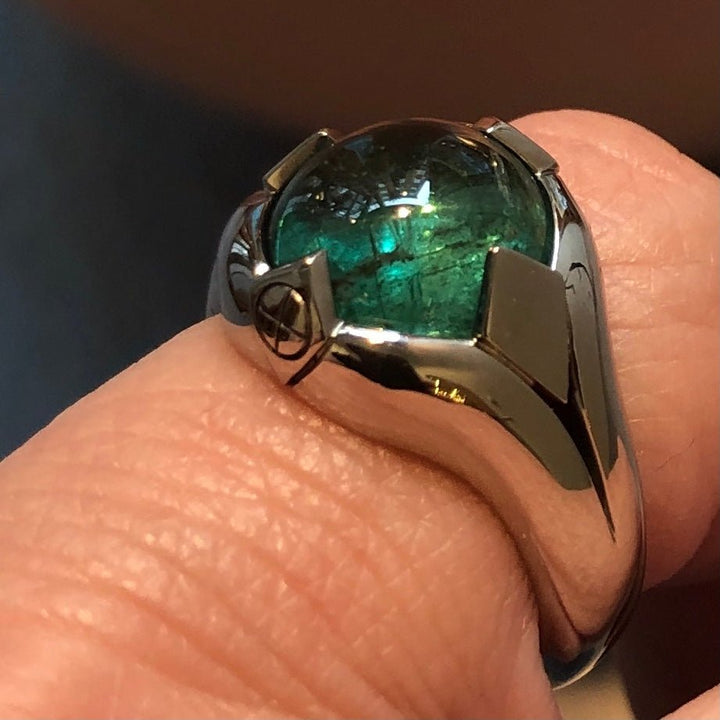 Handgjord ring i 18k guld med stor smaragd, visad på finger i närbild