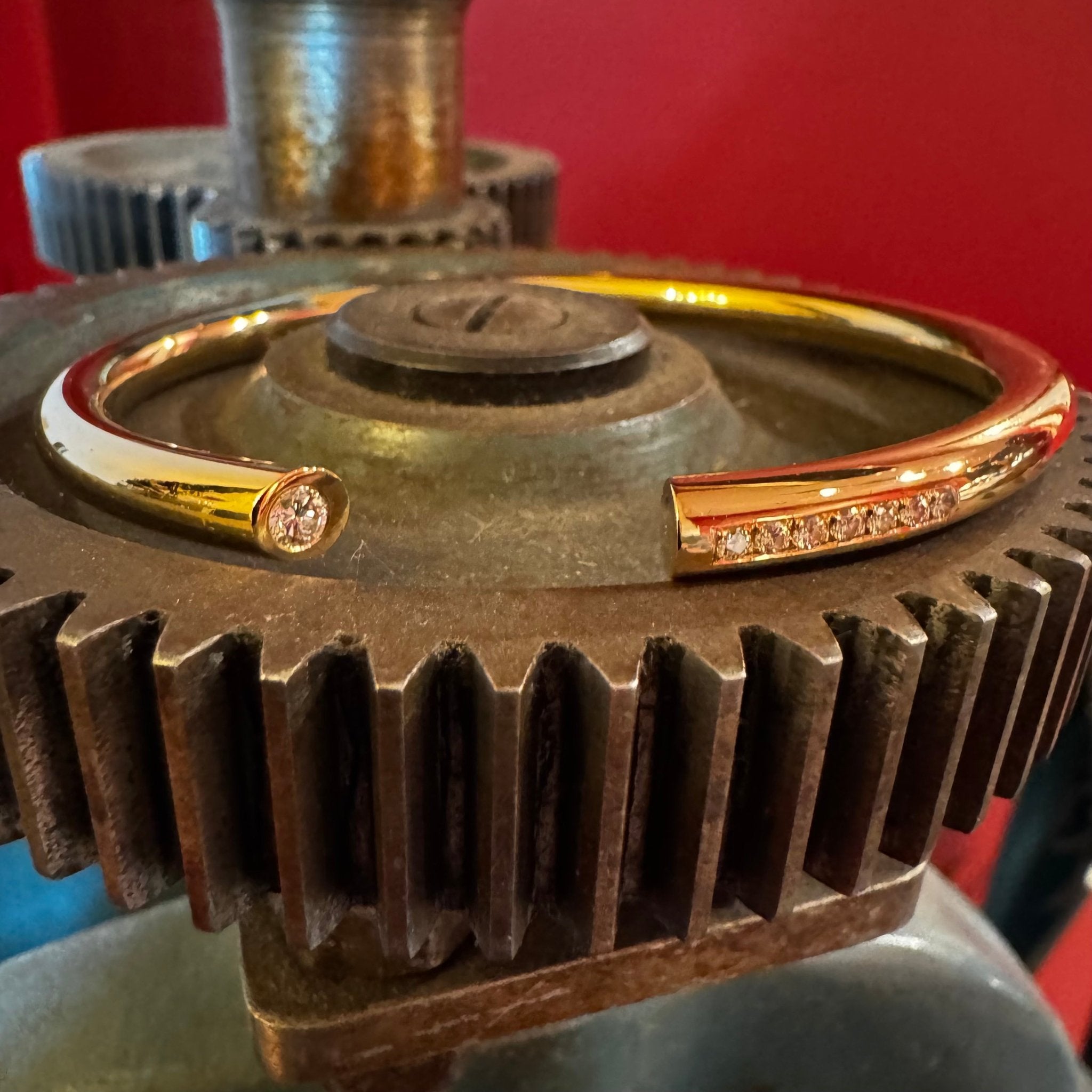 Handgjort armband i kundens guld med diamanter, visat på kugghjul i verkstadsmiljö