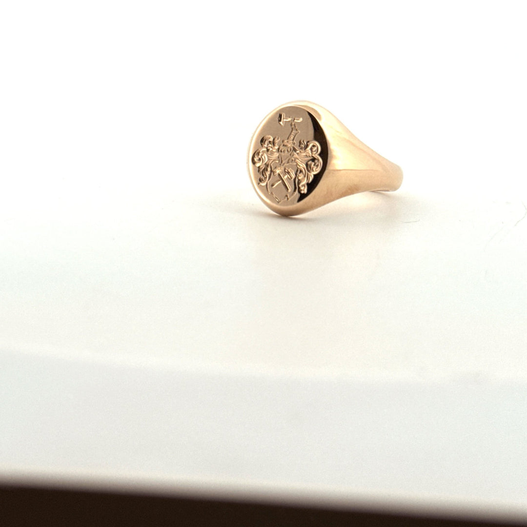 Handsmidd klackring i guld med graverad symbol, snett uppifrån