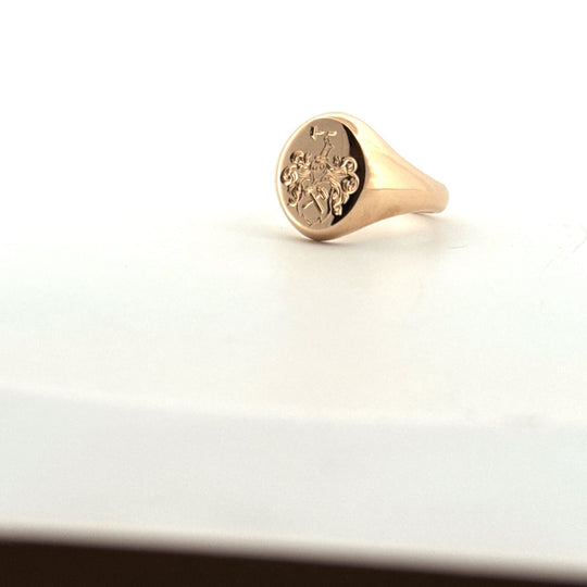 Handsmidd klackring i guld med graverad symbol, snett uppifrån