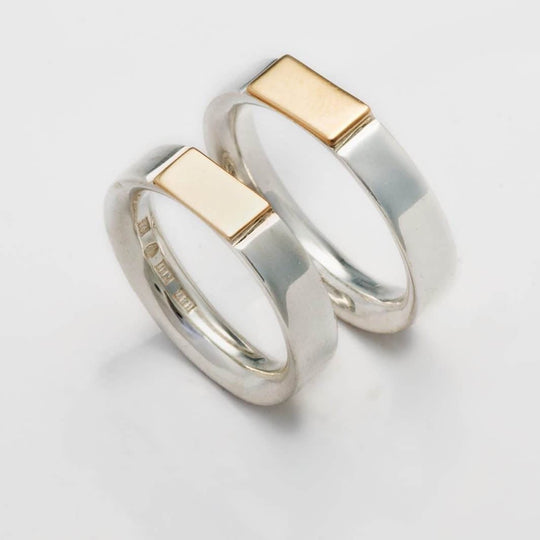 Ringen ”Som en klackring men ändå inte” i silver och guld på vit bakgrund – Ett Rum För Smycken